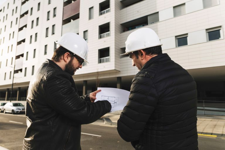 Dos técnicos viendo el plano de un edificio mientras lo están viendo.