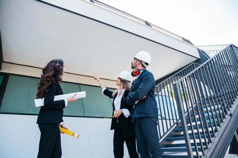 Varios arquitectos con casco revisando la fachada de un edificio.