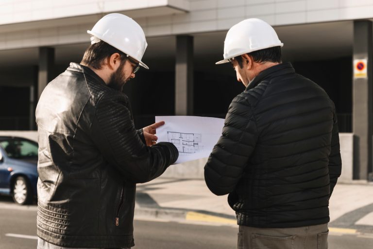 Dos técnicos revisando un edificio con un plano en la mano